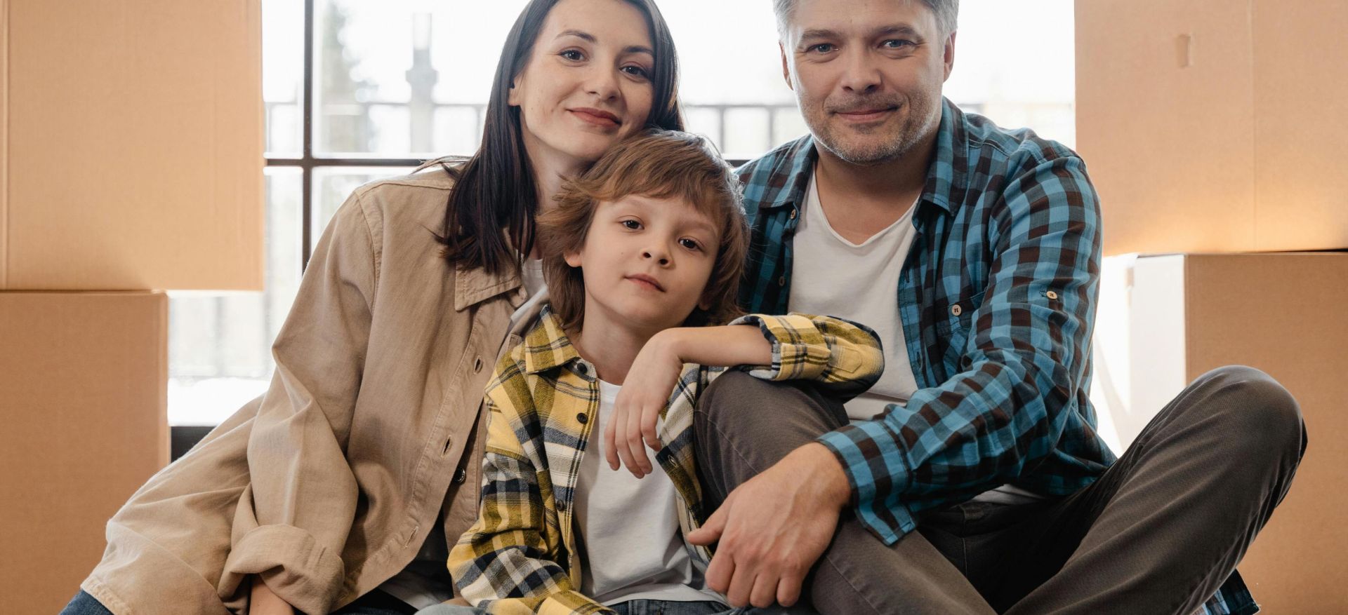 Happy family sitting together in their new home surrounded by moving boxes.